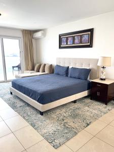 Sunset Beach View - Luxury Studio next to The Morgan Resort في Maho Reef: غرفة نوم بسرير ازرق واريكة