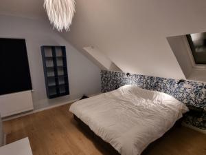1 dormitorio con cama blanca y lámpara de araña en Gîte 'Il y a' 11 à 13 pers #Nature #Familles #Calme #Pas d'abus d'alcool en Marche-en-Famenne