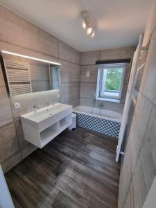 uma casa de banho com um lavatório, uma banheira e um espelho. em Gîte 'Il y a' 11 à 13 pers #Nature #Familles #Calme #Pas d'abus d'alcool em Marche-en-Famenne