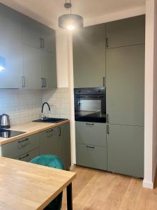 cocina con armarios grises, fregadero y mesa en Airport Green Apartment KL21 - free parking, en Varsovia