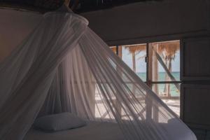 a bed with a white canopy and a window at Cabanas ecoturisticas Costa Maya in Mahahual