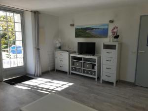 ein Wohnzimmer mit einem TV, einer Kommode und einem Fenster in der Unterkunft Domaine de Bordaberry in Urrugne