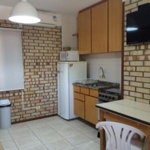een keuken met een witte koelkast en een wastafel bij Bombinhas Quinta do Mar Complexo A in Bombinhas