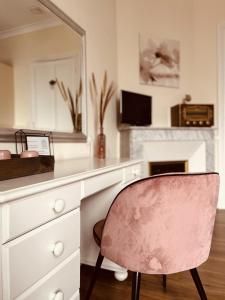 una sedia rosa seduta di fronte a una scrivania con specchio di La Maison de Louisette a Le Faouët