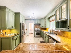 uma cozinha com armários verdes, um lavatório e um frigorífico em Villa Sea Haven at Orange Hill Beach - Private Pool em Nassau