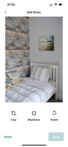una camera con letto bianco e testiera in legno di Cosy seaside cottage a Criccieth