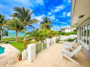 a patio with a white fence and palm trees at Villa Sea Haven at Orange Hill Beach - Private Pool in Nassau