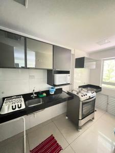 uma cozinha com um lavatório e um fogão forno superior em Prédio Solar do Atlântico - Apartamento lateral em Tambaú em João Pessoa