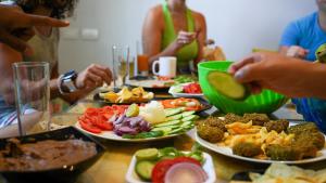 Rafiki Hostels - Dahab في دهب: مجموعة من الناس يجلسون حول طاولة مع أطباق من الطعام