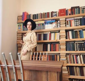 Eine Frau steht vor einem Bücherregal in der Unterkunft Inaisi Hotel in Kutaissi