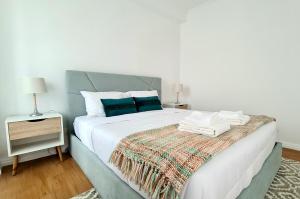 a bedroom with a large white bed with blue pillows at Santa Clara Apartments in Ponta Delgada