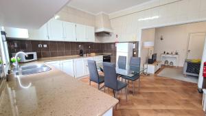 a kitchen with white cabinets and a table and chairs at Santa Clara Apartments in Ponta Delgada