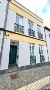 una casa bianca con porta verde e balcone di Santa Clara Apartments a Ponta Delgada