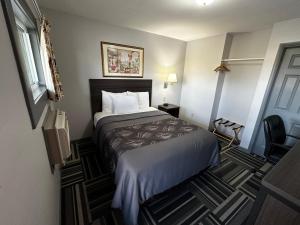 a hotel room with a bed and a chair at Relax Inn - Saginaw in Saginaw