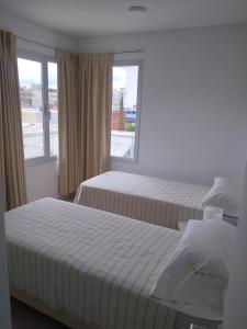 a hotel room with two beds and a window at Marea I in Puerto Madryn