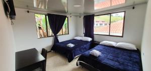 2 Betten in einem Zimmer mit 2 Fenstern in der Unterkunft Alojamiento Blue Sky in Machetá