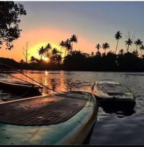 two boats sitting in the water at sunset at Mangue House 2 in Barra de Guaratiba