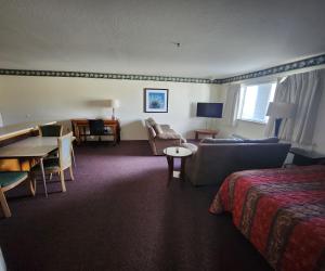 クレセントシティにあるBayview Innのベッド、ソファ、テーブルが備わるホテルルームです。