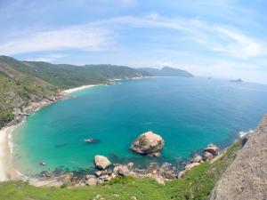 a beach with a large rock in the water at Mangue House 2 in Barra de Guaratiba