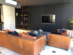 a living room with leather couches and a television at TOP RENTALS TOWER LE BLEU RIVERA in Buenos Aires