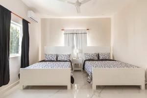 2 Betten in einem Zimmer mit weißen Wänden und Fenstern in der Unterkunft The Green Palms 5 Bedroom villa with pool / garden in San Felipe de Puerto Plata