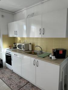 a kitchen with white cabinets and a sink at Fly Airport Residences & Therme-SELF CHECK-IN in Otopeni +28 photos