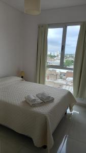a bedroom with a bed with white sheets and a large window at CENTRO NORTE ll a 400 mts del centro con cochera incluida in Bahía Blanca