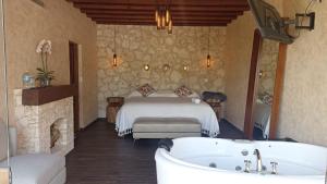 1 dormitorio con cama y bañera en Zidada Hotel and Chalets, en Bernal