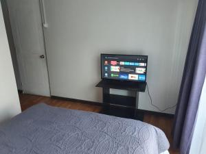 1 dormitorio con 1 cama y mesa con TV en Hostal del Rio, en Concepción