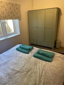 ein Schlafzimmer mit zwei grünen Kissen auf einem Bett in der Unterkunft Crab Cottage in Wells next the Sea