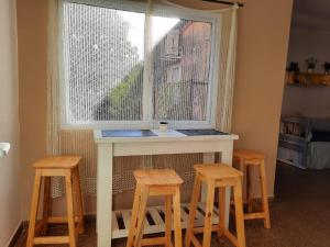 una mesa con tres taburetes delante de una ventana en Alma viajera en Posadas