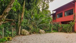 una casa rossa con recinzione e alberi di Canto dos Pássaros Suítes a Ubatuba