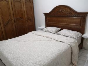 a bed with a wooden headboard and two pillows at Adam appart in Dar Bouazza