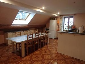 cocina con mesa, sillas y nevera en Le P'tit Bonheur, en Chilly-sur-Salins