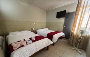 a hotel room with two beds and a fan at Hotel los angeles in Huaral