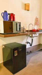 une cuisine avec un four micro-ondes sur une étagère et un comptoir dans l'établissement Canto dos Pássaros Suítes, à Ubatuba