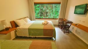 - une chambre avec un lit avec un animal rembourré dans l'établissement Canto dos Pássaros Suítes, à Ubatuba