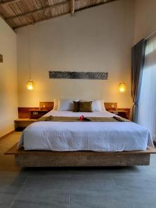 a bedroom with a large bed with two lights on the wall at Drift Hideaway in Kuta Lombok