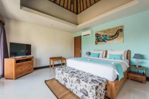 a bedroom with a large bed and a flat screen tv at Villa Lacasa2- modern tropical 2BR Villa with butler in Legian