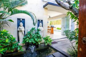 dos estatuas en el patio de una casa con un estanque en Villa Lacasa3 -Modern tropical 3BR Villa with butler, en Legian
