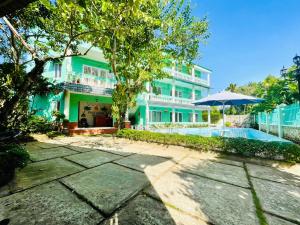 ein blaues Gebäude mit einem Swimmingpool und einem Sonnenschirm in der Unterkunft Phu Long Resort & Bar Phu Quoc in Phu Quoc