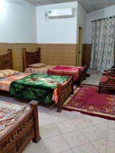 Five Giants Lahore Homestay في لاهور: غرفه بثلاث اسره وثلاث سجاد