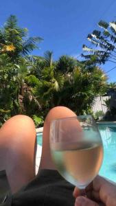 a person holding a glass of wine in front of a pool at Art Deco Villa Heated Pool Jacuzzi Very Private house on a quite street close to Design District 10 minutes from the Beach - in Miami