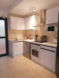 a kitchen with white cabinets and stainless steel appliances at Apartment by the sea with WIFI & Netflix in El Cotillo