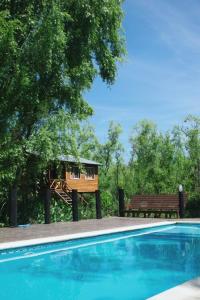 a swimming pool with a house and a bench at ComplejoGovinda in Tigre