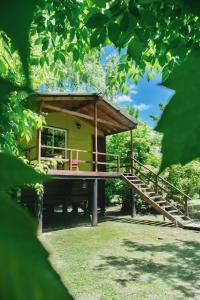 a small yellow house with a wooden porch and stairs at ComplejoGovinda in Tigre