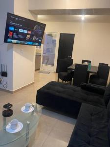 a living room with a black couch and a tv at Paradisiaca casa con Laguna y Alberca in Veracruz