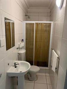 uma casa de banho branca com um WC e um lavatório em 14th On Clifford Guest House em East London