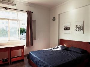 a bedroom with a bed and a desk and a window at Nguyen Shack - Sai Gon in Ho Chi Minh City