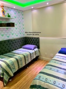 two beds in a room with green lights on the wall at Lazer completo com Vistas de um Belo Horizonte in Belo Horizonte